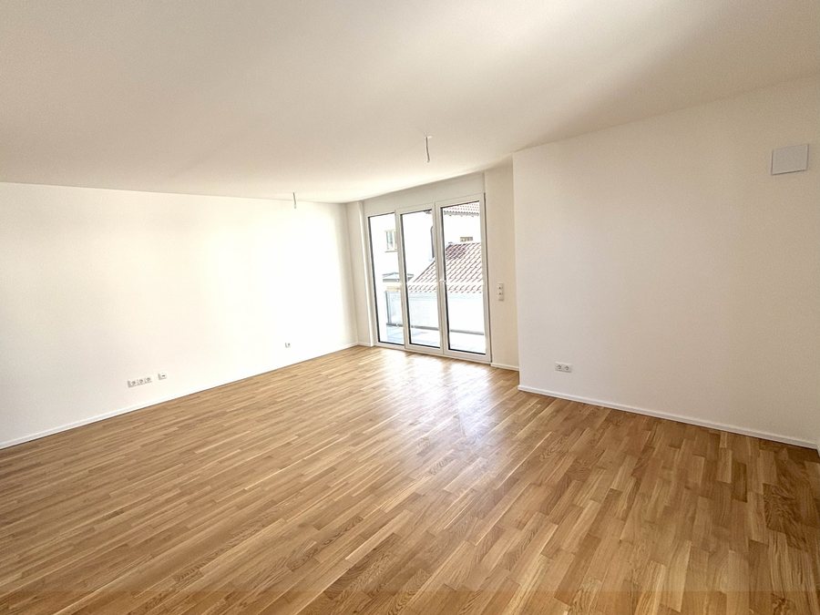 Heller Wohnraum mit Eichenparkett und Fenstertüren zum Balkon